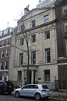 A light tan stone townhouse with an entrance portico