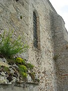 Mur de l'église présentant des ouvertures étroites typiques des églises du XIIIe siècle.