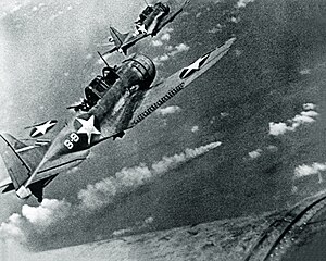 Dua pesawat SBD mendekati Kapal penjelajah Jepang Mikuma  (2) yang sedang terbakar (tengah).