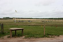 Photograph of a wide shooting range with shooters firing at bullseye targets