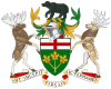 A central shield with the upper part showing the red cross of St. George and the lower part showing three golden maple leaves on a green background. There is a black bear on top of a knight's helmet above the shield with a moose to the left and a Canadian deer to the right. The province's motto "Ut incepit Fidelis sic permanent", Latin for "Loyal she began, loyal she remains" is written below the crest.