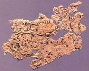 Fragment of ancient Chinese paper map with features in black ink, found on the chest of the occupant of Tomb 5 of Fangmatan, Gansu in China in 1986, from early Western Han, 2nd century BC, 5.6 cm × 2.6 cm (2.2 in × 1.0 in).