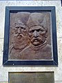 کتیبهٔ روی ستون یادبود که تصویر میرزا کوچک خان و میرزا محمدرضا کلهر را نشان می‌دهد