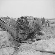 A Churchill AVRE, carrying a fascine, crosses a ditch using an already deployed fascine, (1943)