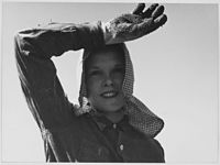 Mladá dívka vzhlédla od práce, sbírá brambory. Edison, Kern County, Kalifornie.