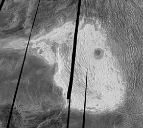 Радарный снимок «Магеллана». Горы Максвелла — светлая область. Слева внизу — плато Лакшми, справа — тессера Фортуны. Тёмный кратер правее и выше центра — Клеопатра. Чёрные полоски — незаснятые места