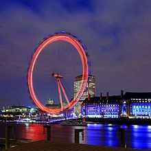 A ferris wheel blurs into a neon circle.