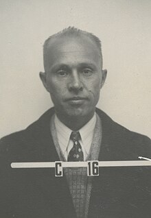 Head and shoulders mug shot of middle-aged man in suit and tie. Lettering reads "C 16"