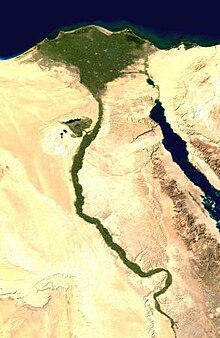 Imagem de satélite mostrando o vale verde percorrendo o deserto ao longo do curso do rio. No topo o vale se abre como um leque, e acaba no oceano azul profundo.