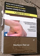 A cigarette package features warning text and a large photograph of a person with a large side wound.