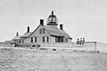 The original lighthouse and keeper's house. Note the three small children seated in front.