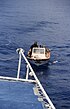 Mönch mit Motorboot und Mobiltelefon holt eine Proviant-Lieferung von einem Ausflugsschiff (2002)