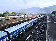 Outdoor train station, with long passenger train