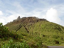Photographie couleur du sommet d'une moyenne montagne partiellement recouverte d'une végétation tropicale.