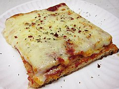A slice of Sicilian pizza topped with red pepper and herbs