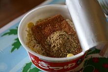 An opened cup of an instant noodle brand that is packaged with dehydrated fried tofu