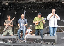 Rawlins Cross performing at Riverfest Elora in 2018. From left: Brian Bourne (Chapman Stick), Joey Kitson (vocals), Howie Southwood (in back, on drums), Dave Panting (mandolin), Ian McKinnon (tin whistle). Not pictured: Geoff Panting