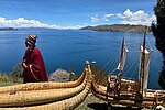 A man in traditional clothes and reed boats at the lake shore