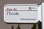 Zweisprachiges Schild in Käerjeng: Schoulstrooss (luxemburgisch) / Rue de l'École (franz. für Schulstraße)