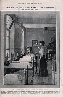 Photogravure copy of a photograph of children lying in a row of beds in a ward, being given instruction by a woman standing at the foot of the beds. A female nurse in uniform is in the background.