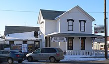 Two-story wooden building with "Glur's Tavern" signs and several modern beer signs