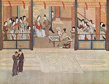 Malba skupiny mužů i žen ve splývavých róbách v lehce stavěném pavilónu, uprostřed vznešená dáma sedí před umělcem ji malujícím.