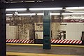 Dunkle Ablagerungen von einsickerndem Wasser bedecken Teile einer eigentlich weißen Hintergleiswand eines U-Bahnhofs
