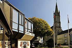 Photographie en couleurs de l'entrée de la mairie avec vue sur le clocher de l'église.