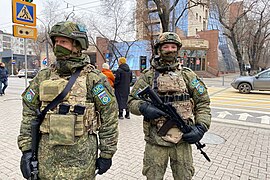 Два военнослужащих России в составе Коллективных миротворческих сил ОДКБ на фоне входа на станцию «Жибек Жолы»
