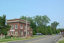 A large square red brick building on a triangular lot