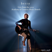Cover artwork of "Betty" live version, featuring Swift performing on a guitar, against a glowing stagelight