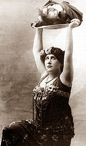 young woman in ancient middle-eastern costume holding a tray on which is a severed male human head