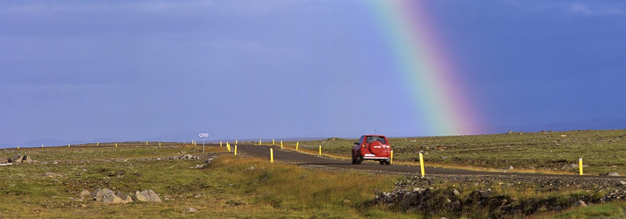 Rainbow a lonely road and a red car, Hraunhafnartangi, North Iceland, Iceland