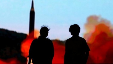 People walk in front of a monitor showing news of North Korea's fresh threat in Tokyo, Japan, August 10, 2017. REUTERS/Toru Hanai