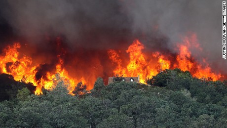 Flames from the Rocky Fire approach a house on Friday,  July 31, in Lower Lake, California. 