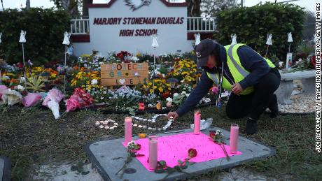 PARKLAND, FLORIDA - FEBRUARY 14: Wendy Behrend, a school crossing guard who was on duty one year ago when a shooter opened fire in Marjory Stoneman Douglas High School pays her respects at a memorial setup for those killed on February 14, 2019 in Parkland,  Florida. 