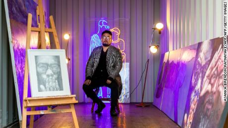This picture taken on May 28, 2019 shows Chinese cartoonist Badiucao standing behind his artwork titled &#39;Light&#39; in his studio in Melbourne. - Badiucao, a Chinese cartoonist whose anonymous political satire earned him comparisons with Banksy -- and the wrath of Beijing -- has outed himself as a former law school student who became politicised after watching a Tiananmen Square documentary in a dorm room. (Photo by Asanka Brendon Ratnayake / AFP) / RESTRICTED TO EDITORIAL USE - MANDATORY MENTION OF THE ARTIST UPON PUBLICATION - TO ILLUSTRATE THE EVENT AS SPECIFIED IN THE CAPTION
To go with AFP story Hong Kong-China-politics-art, INTERVIEW by Alice Philipson in Hong Kong and Asanka Brendon Ratnayake in Melbourne /         (Photo credit should read ASANKA BRENDON RATNAYAKE/AFP/Getty Images)