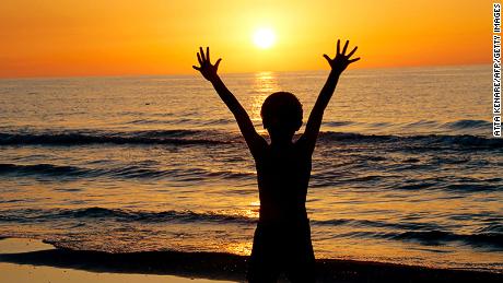 An Iranian child raises his hands at sunset at a beach in the Caspian Sea port city of Mahmoud Abad, in northern Mazandaran province on June 16, 2016.
 / AFP / ATTA KENARE        (Photo credit should read ATTA KENARE/AFP/Getty Images)