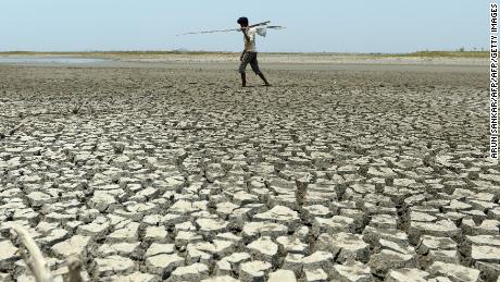 An Indian man walks over the parched bed of a reservoir on the outskirts of Chennai on May 17, 2017