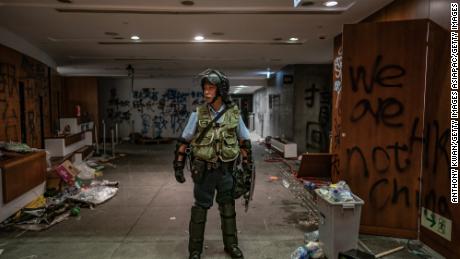 HONG KONG - JULY 2: A riot police stands near graffiti inside the Legislative Council building after it was damaged by demonstrators during a protest on July 2, 2019 in Hong Kong, China. housands of pro-democracy protesters faced off with riot police on Monday during the 22nd anniversary of Hong Kong&#39;s return to Chinese rule as riot police officers used batons and pepper spray to push back demonstrators. The city&#39;s embattled leader Carrie Lam watched a flag-raising ceremony on a video display from inside a convention centre, citing bad weather, as water-filled barricades were set up around the exhibition centre. (Photo by Anthony Kwan/Getty Images)