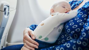 a woman holding a sleeping baby on an airplane