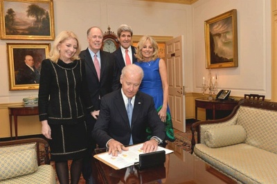 With U.S. Secretary of State John Kerry and her family looking on, Vice President Joe Biden signs the appointment papers for Catherine Russell to become the U.S. Ambassador-at-Large for Global Women's Issues at the U.S. Department of State in Washington, D.C., on January 17, 2014.
