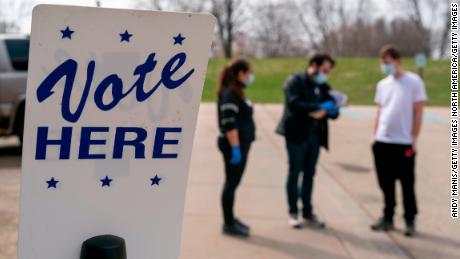 MADISON, WI - APRIL 07: Poll worker Josh Harrison, center, works with Chad Donahue, right, during curbside voting on April 7, 2020 in Madison, Wisconsin. Residents in Wisconsin went to the polls a day after the U.S. Supreme Court voted against an extension of the absentee ballot deadline in the state. Because of the coronavirus, the number of polling places was drastically reduced. (Photo by Andy Manis/Getty Images)