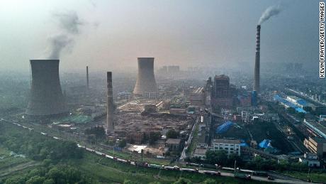 In this file photo, a Chinese state owned coal fired power plant is seen near a large floating solar farm project under construction by the Sungrow Power Supply Company on a lake caused by a collapsed and flooded coal mine on June 16, 2017 in Huainan, Anhui province, China.