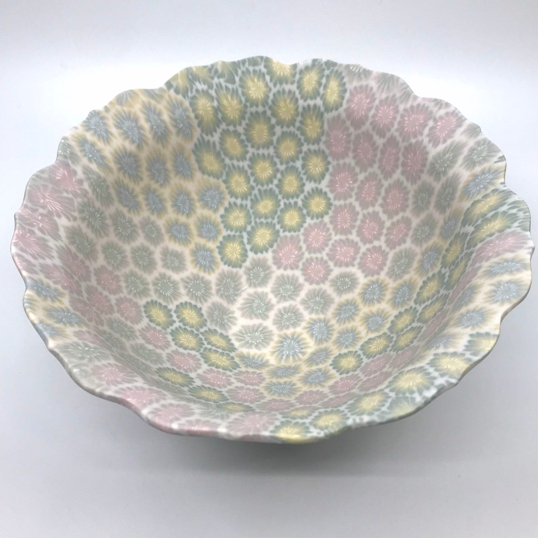 Multicolour ceramic floral bowl in pink, blue, and yellow, with delicate scalloped edges made with the nerikomi ceramic technique.