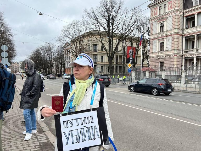 Женщина демонстрирует российский паспорт напротив российского посольства в Риге, Латвия