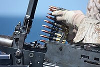Морпех 24-го эомп снаряжает ленту в пулемёт М2 на борту десантного корабля-дока USS Carter Hall (LSD-50), 24 сентября 2010
