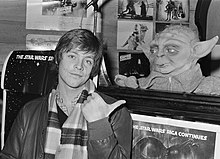 A photograph of Mark Hamill in 1980, promoting The Empire Strikes Back while pointing at a puppet of Yoda
