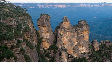 The Three Sisters towering above the Jamison Valley. The lighter coloured orange/yellow sections indicate fresh rock, exposed by recent erosion.