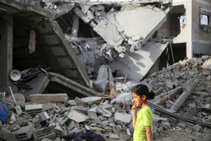 4月25日、パレスチナ自治区ガザの最南端ラファで、イスラエル軍の攻撃で壊れた住宅の横を歩くパレスチナ人の少女=ロイター